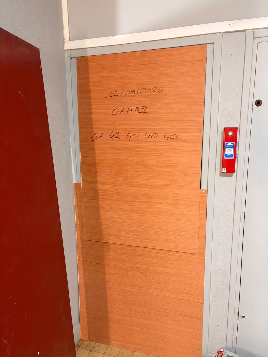 Fermeture provisoire de nuit d'une porte par panneau de contreplaqué dans un couloir d'immeuble